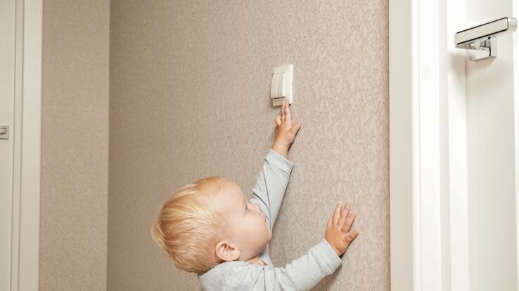 Ein kleines Kind streckt sich, um an den Lichtschalter zu kommen.
