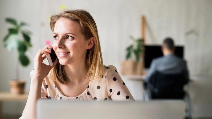 Eine Frau informiert sich am Telefon über Baufinanzierung.