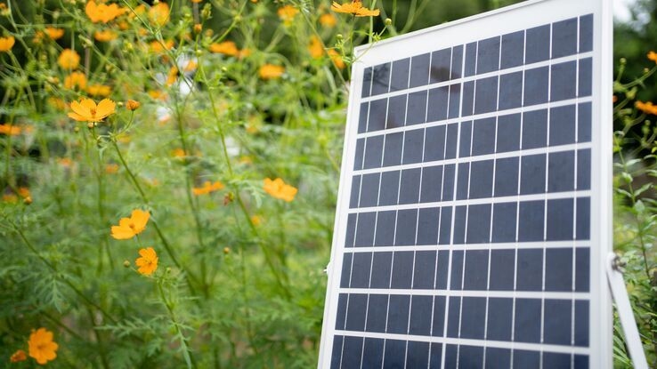 Eine kleine Solaranlage steht im Garten auf der Wiese.