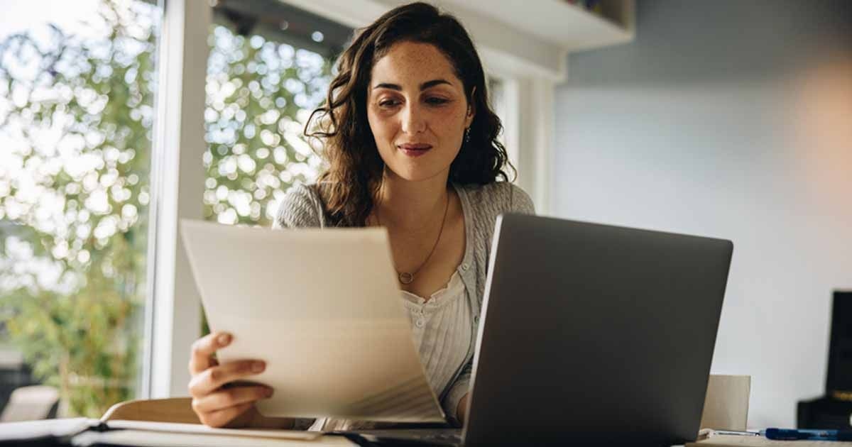 Eine Frau sitzt am Laptop und prüft ihren Schufa-Eintrag.