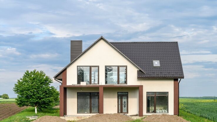 Abgebildet ist ein Passivhaus mit dunklem Dach in einer ländlichen Umgebung.