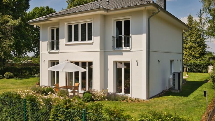 Ein Einfamilienhaus mit speziellem Baustil ist umgeben von einem Garten.