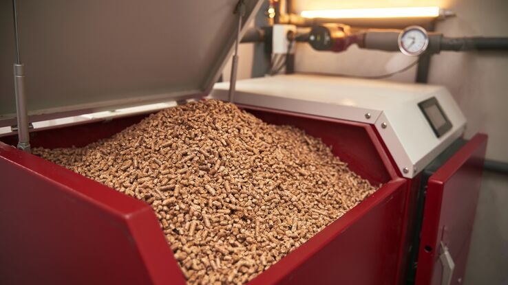 Abgebildet sind Holzpellets in einem großen roten Behälter.