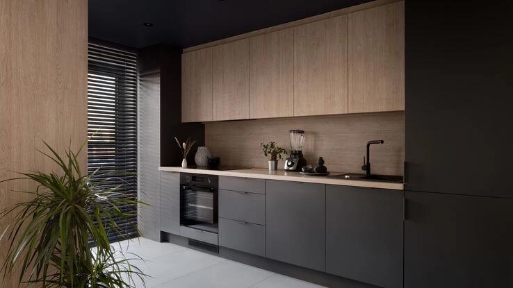 Zu sehen ist eine moderne schwarze Küche mit Holzschränken.