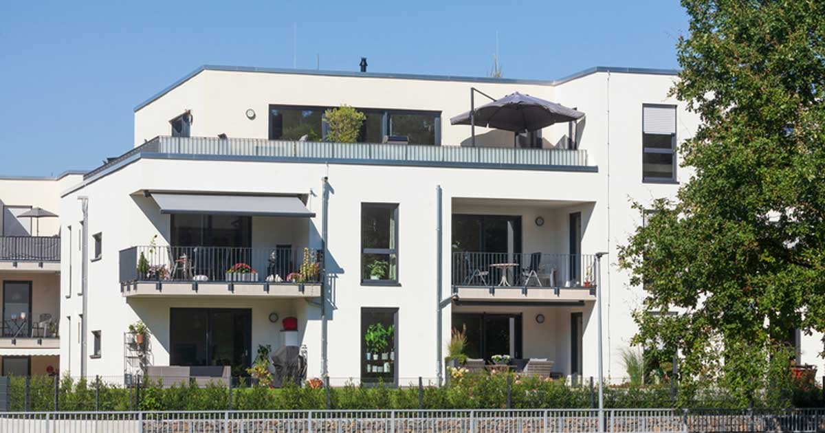 Es ist ein weißes Mehrfamilienhaus zu sehen.