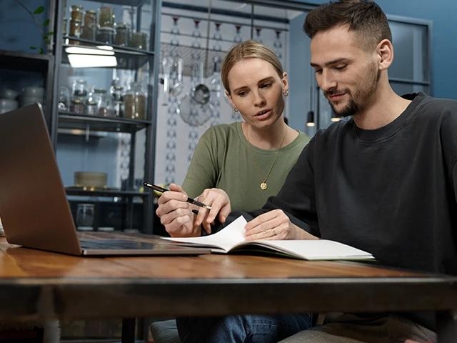 Ein Pärchen prüft ihre Unterlagen und berechnet am Laptop den Zins.