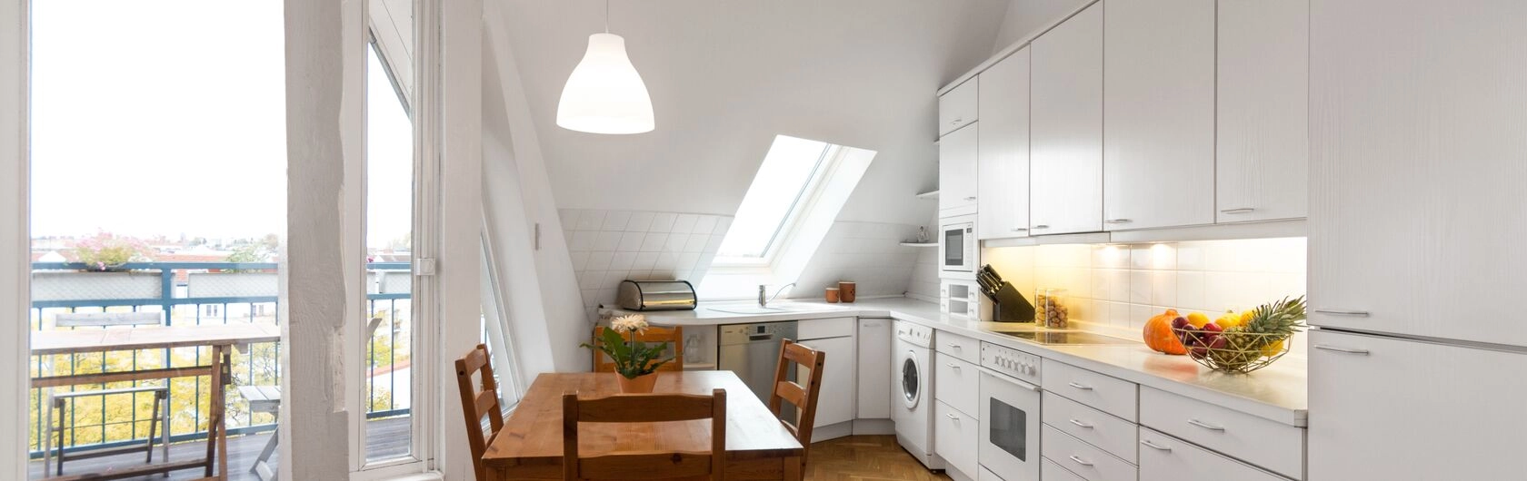 Eine weiße Küche mit einem Holztisch daneben.