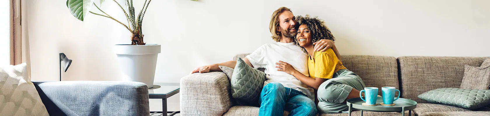 Ein Pärchen sitzt Arm in Arm auf der Couch.