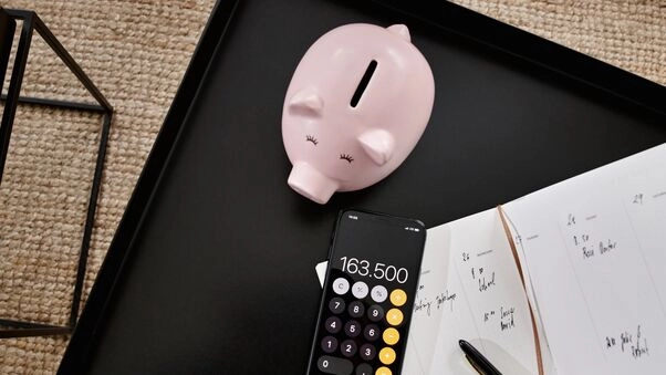 Ein Sparschwein symbolisiert mit dem Taschenrechner ein günstiges Baugeld.