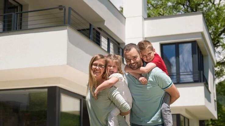 Symboldbild für das KfW-Programm 124: Eine Familie vor ihrem Wohneigentum.