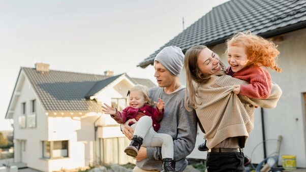 Symboldbild für das KfW-Programm 300: Eine junge Familie vor ihrer Immobilie.