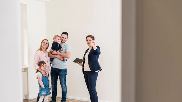 Eine Maklerin zeigt einer Familie eine Wohnung.