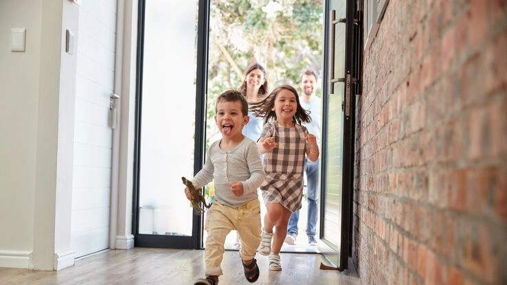 Eine Familie geht in Ihr neu gebautes Haus.