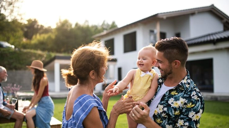 Eine Familie erfreut sich im Garten ihres Neubaus.