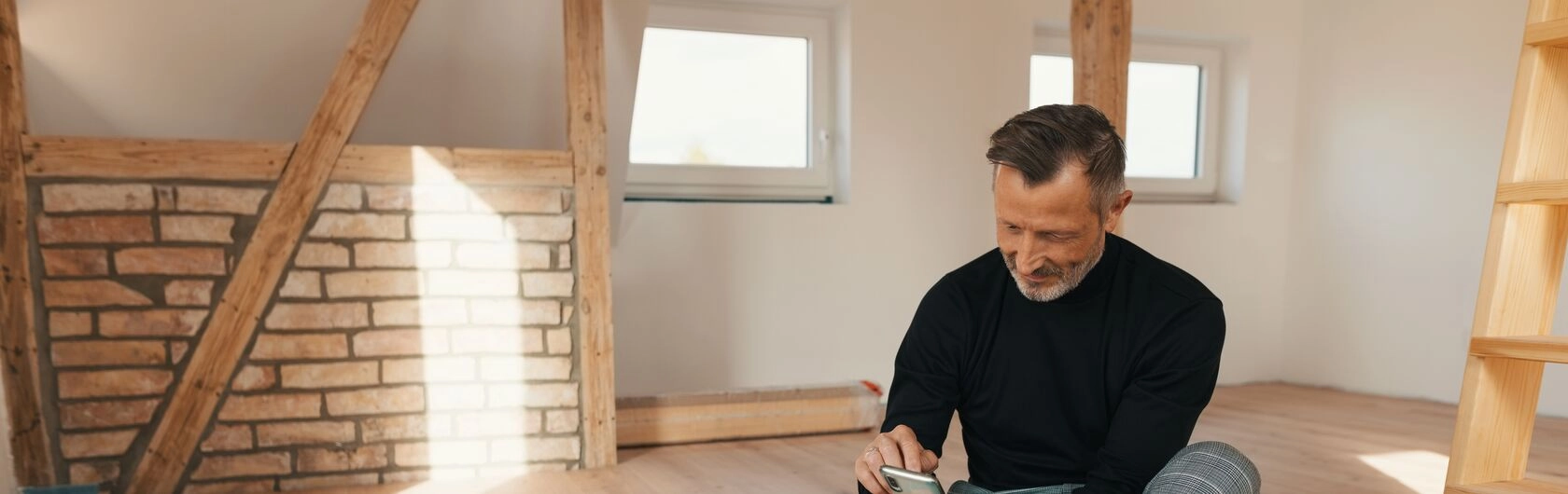 Ein Mann informiert sich auf seinem Smartphone darüber, was die Top acht Fehler bei einer Immobilienfinanzierung sind.