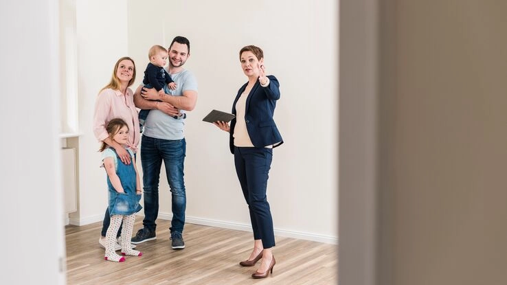 Bei einer Wohnungsbesichtigung stellt die Vermieterin einer Familie die Immobilie vor.