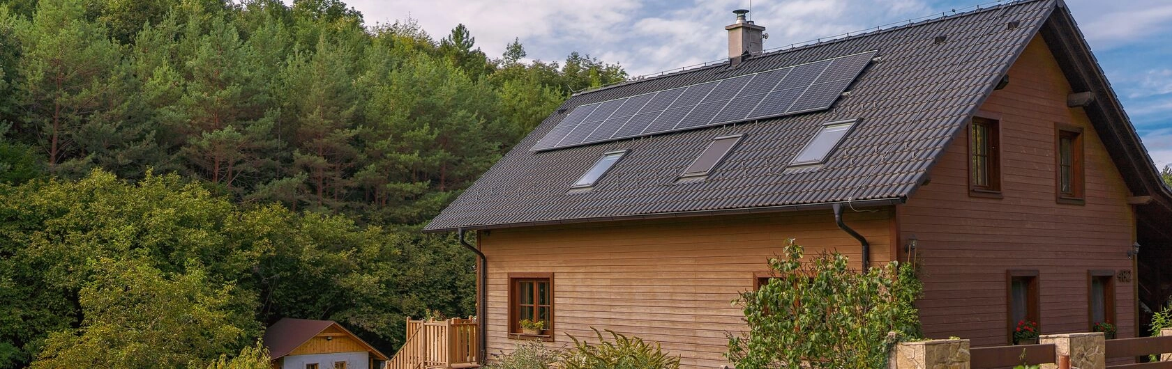 Ein Holzhaus mit Solarpaneelen im Grünen.