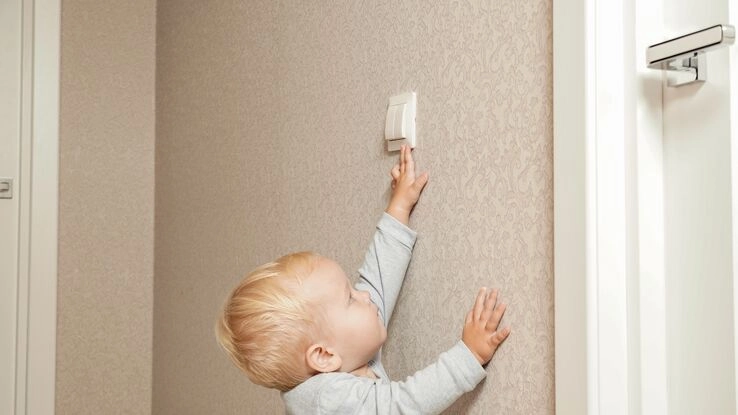Ein Kind schaltet das Licht aus uns macht Stromsparen vor.