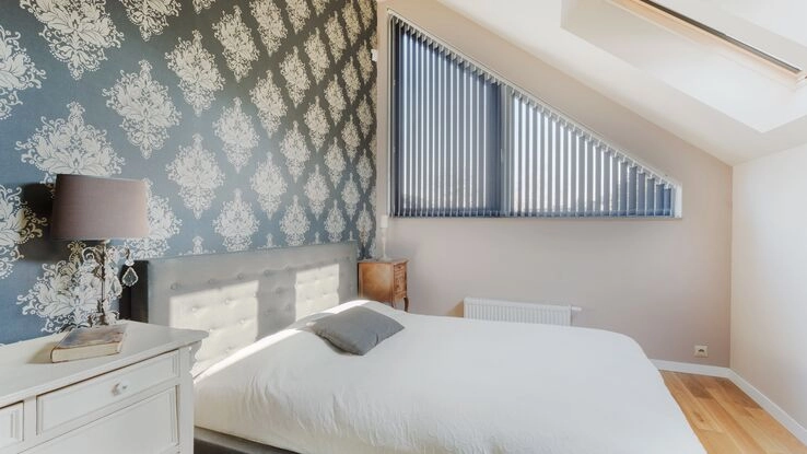Ein gemütliches Schlafzimmer mit einer Mustertapete.