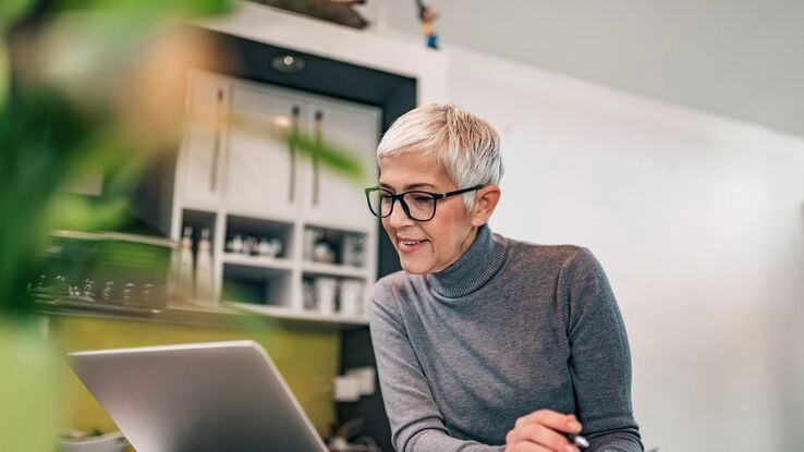 Eine Frau informiert sich an ihrem Laptop über den Immobilienwert.