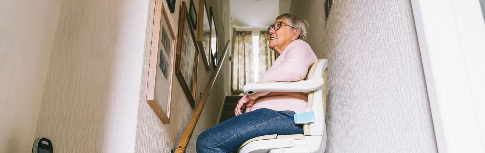 Eine Frau nutzt ihren Treppenlift, um sich im Haus barrierefrei bewegen zu können.