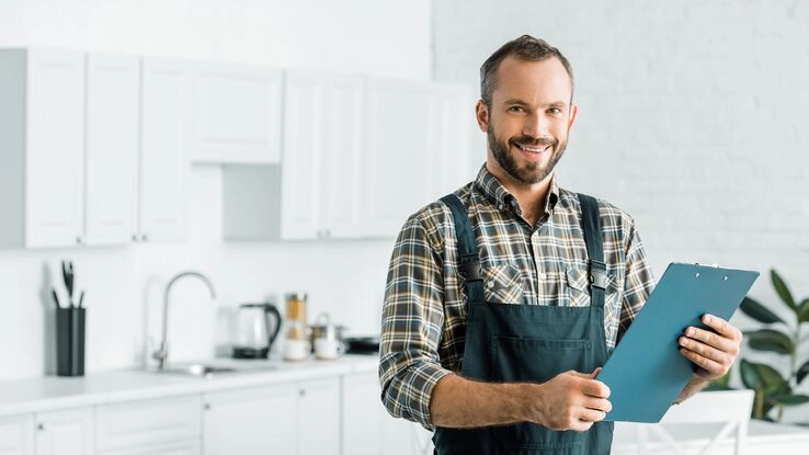 Ein Handwerker steht vor einer neuen Küche. So finden auch Sie persönlich oder online einen Handwerker der zu Ihnen passt.