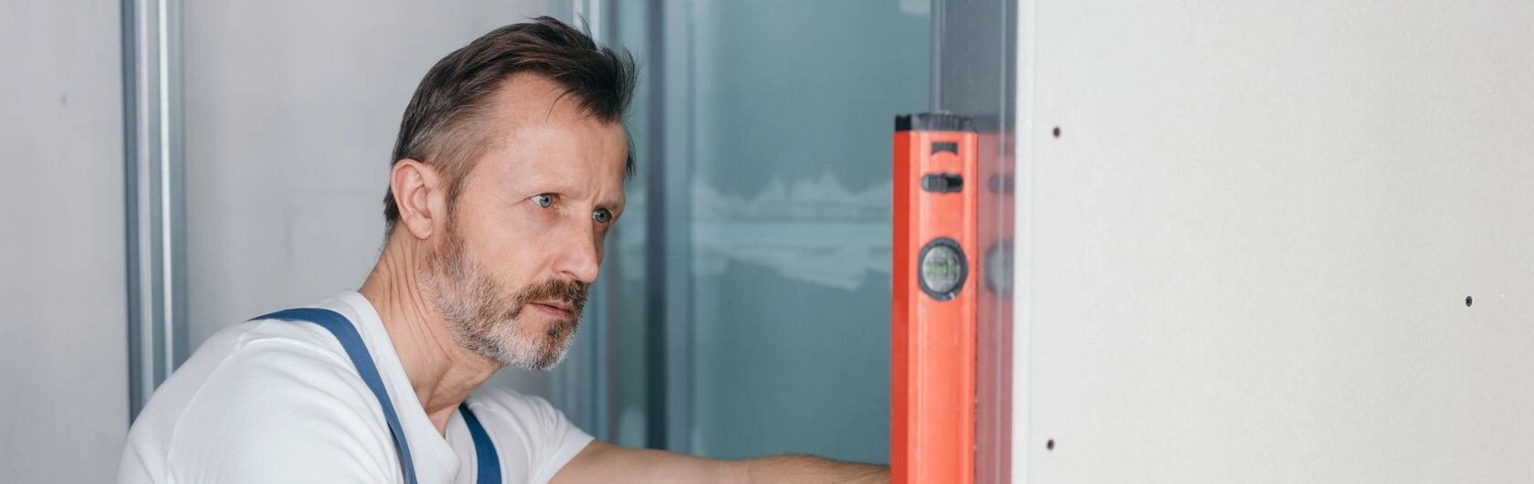 Ein Handwerker schaut mit einer Wasserwaage, ob die Wand gerade ist.