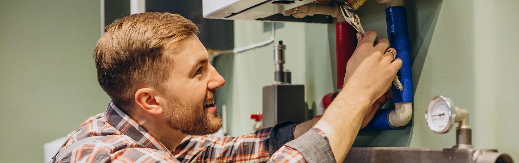 Ein Handwerker prüft und modernisiert eine Heizung um Heizkosten zu sparen.