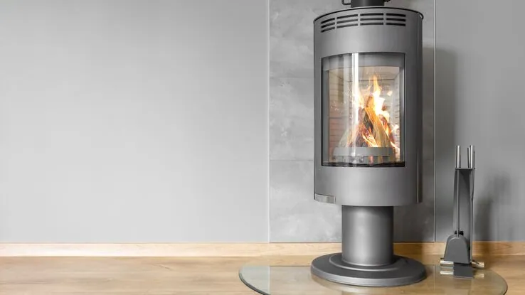 Das Bild zeigt einen modernen Kamin mit grauer Verkleidung mit schönem Feuer zum wärmen.
