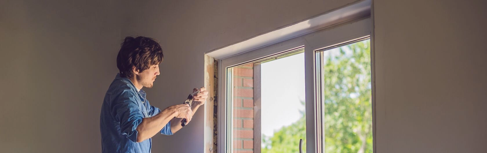 Im Bild sieht man einen Mann, der ein Fenster saniert.