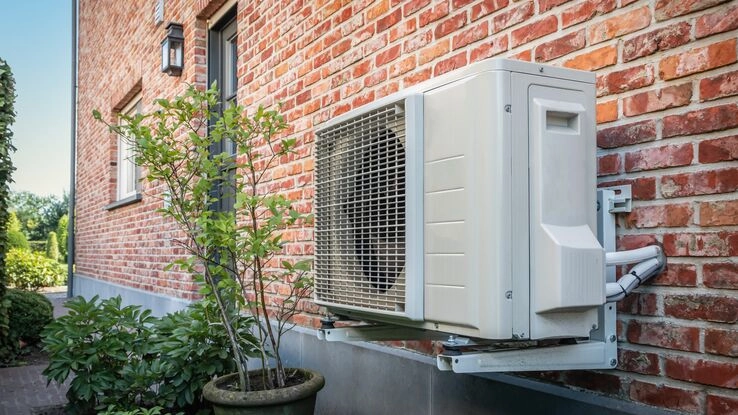 Symboldbild für das KfW-Programm 458: Eine Wärmepumpe an einem Gebäude.