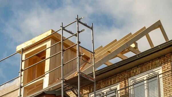 Bauen im Bestand - das Bild von einem Dachgestuhl zeigt dies. Das Haus befindet sich noch im Bau, da auch ein Baugerüst zu sehen ist.