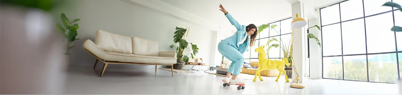 Eine Frau fährt mit einem Skateboard durch ihr Wohnzimmer.