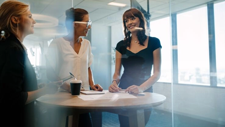 Frauen sprechen bei einer Tasse Kaffee bei der Arbeit.