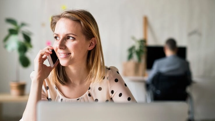 Eine Frau informiert sich am Telefon über Baufinanzierung.
