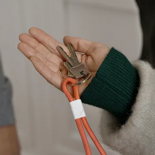 Eine Frau hält einen Schlüssel zur Wohnungstür in der Hand.