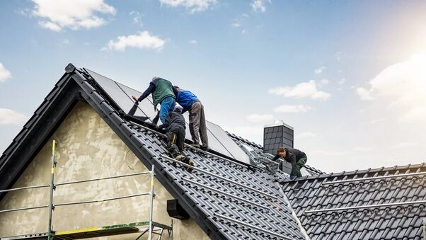 Symboldbild für das KfW-Programm 296: Handwerker installieren eine Photovoltaikanlage auf dem Dach.
