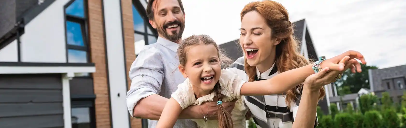 Eine Familie hat sich ihren Traum erfüllt: die eigenen vier Wände. Sie freuen sich im Garten.