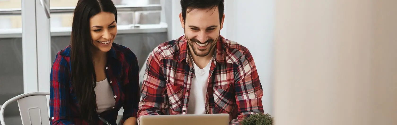 Ein Paar sitzt gemeinsam am Laptop und such eine Immobilie ohne Maklerbüro.