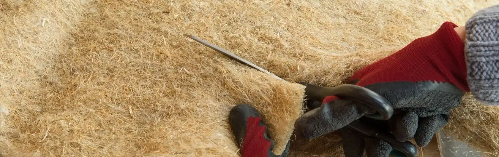 Ein Handwerker schneidet Dämmmaterial für die Dämmung eines Fußbodens.