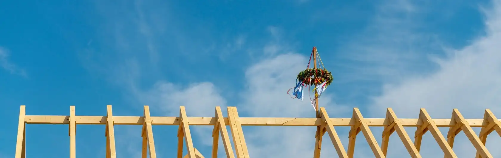 Ein mit einem Kranz geschmückter Dachstuhl für das anstehende Richtfest.