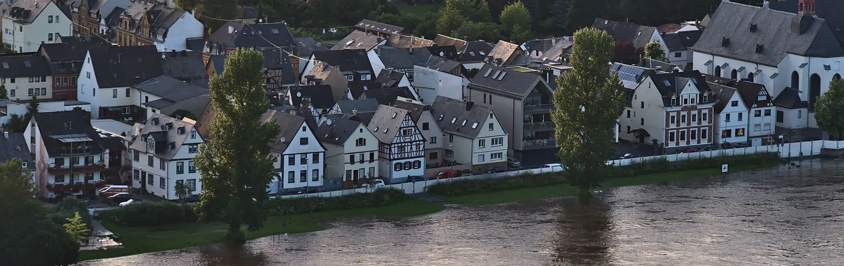 Fachwerkhäuser stehen am Ufer eines Flusses.