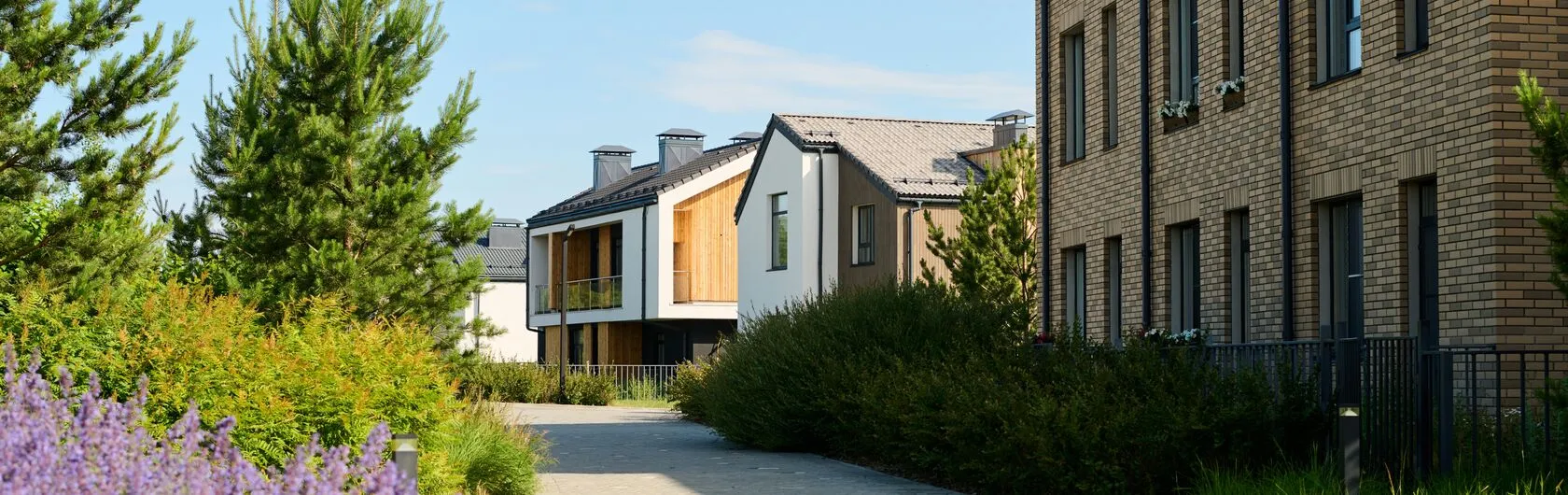Eine Straße mit mehreren Mehrfamilienhäusern und Sträuchern.
