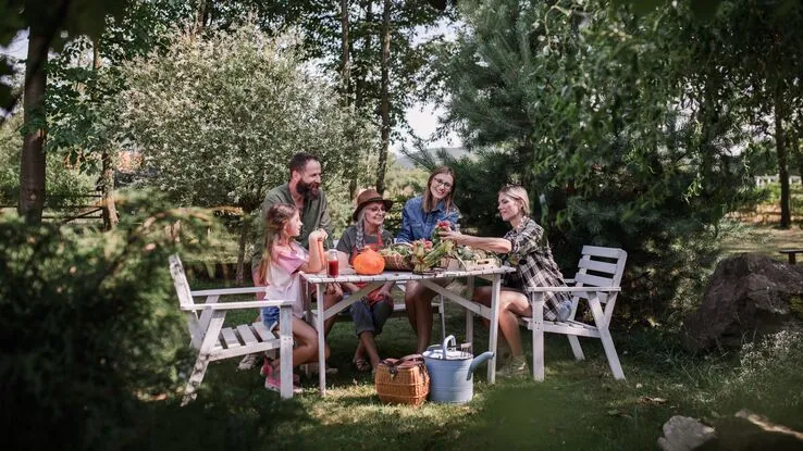 Eine Familie sitzt im eigenen Garten zusammen und feiert ein Fest, nachdem sie ihren Außenbereich neugestaltet haben.
