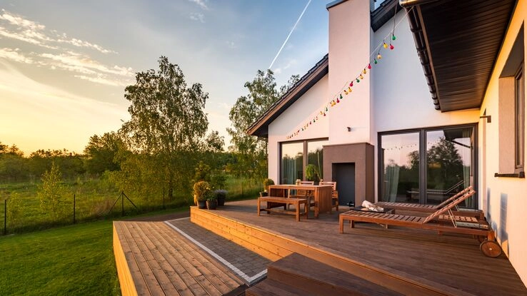 Eine Holzterrasse mit Möbeln im Sonnenuntergang zur Entspannung nach einem stressigen Alltag.