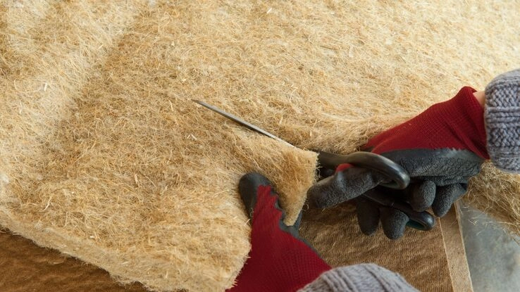 Eine Person schneidet Dämmmaterial für den Kellerboden zurecht.