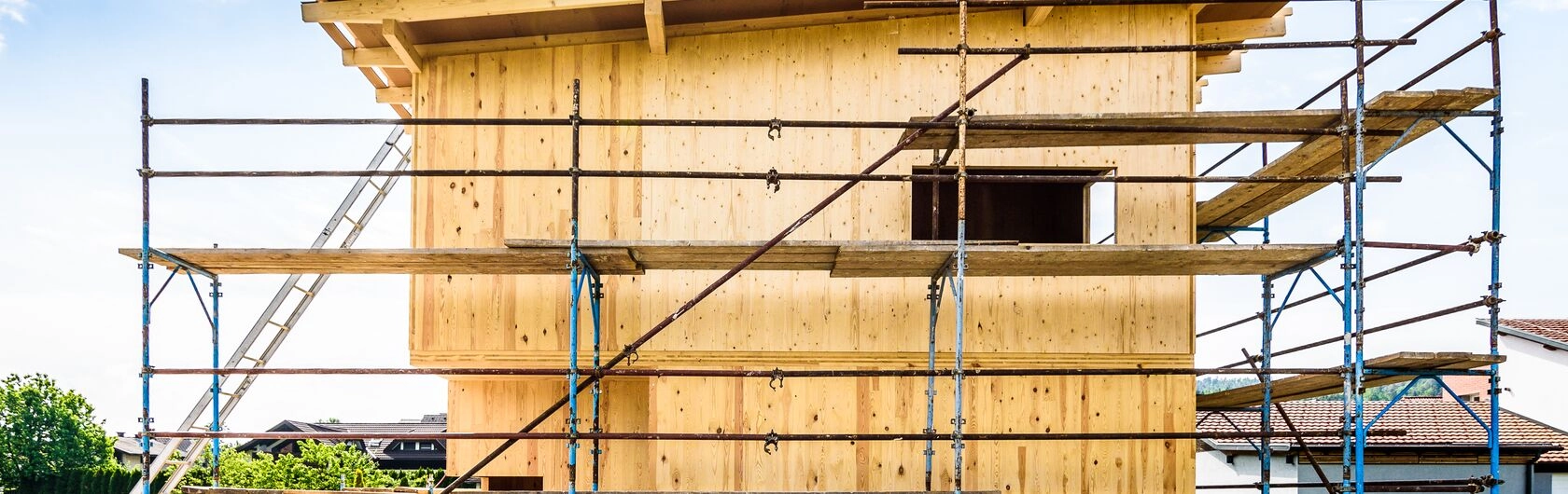 Ein nachhaltiges Holzhaus im Bau um das ein Gerüst steht.