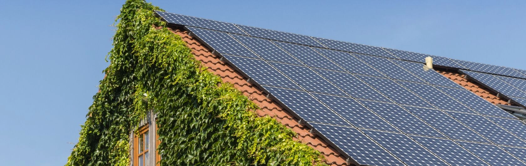 Ein bewachsenes Sonnenhaus mit einer Photovoltaikanlage.