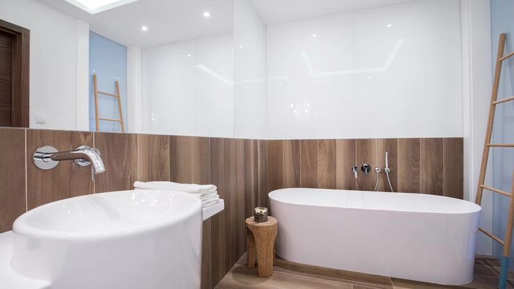 Eine moderne Badewanne mit einer Schmuckrückwand aus Holz.