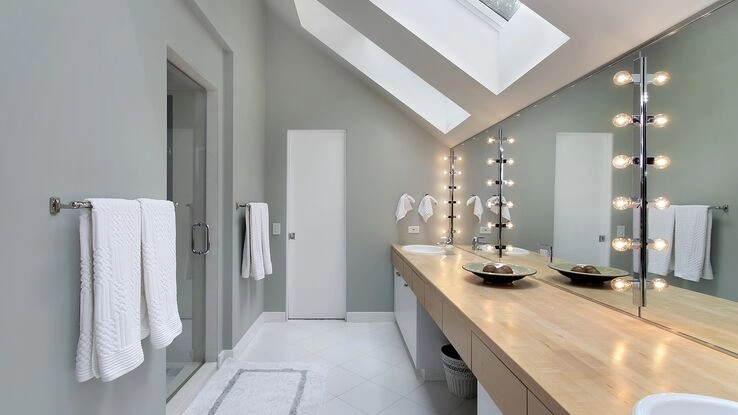 Ein modernes Badezimmer mit Dachschrägen und einer beleuchteten Spiegelfront für mehr Gemütlichkeit 